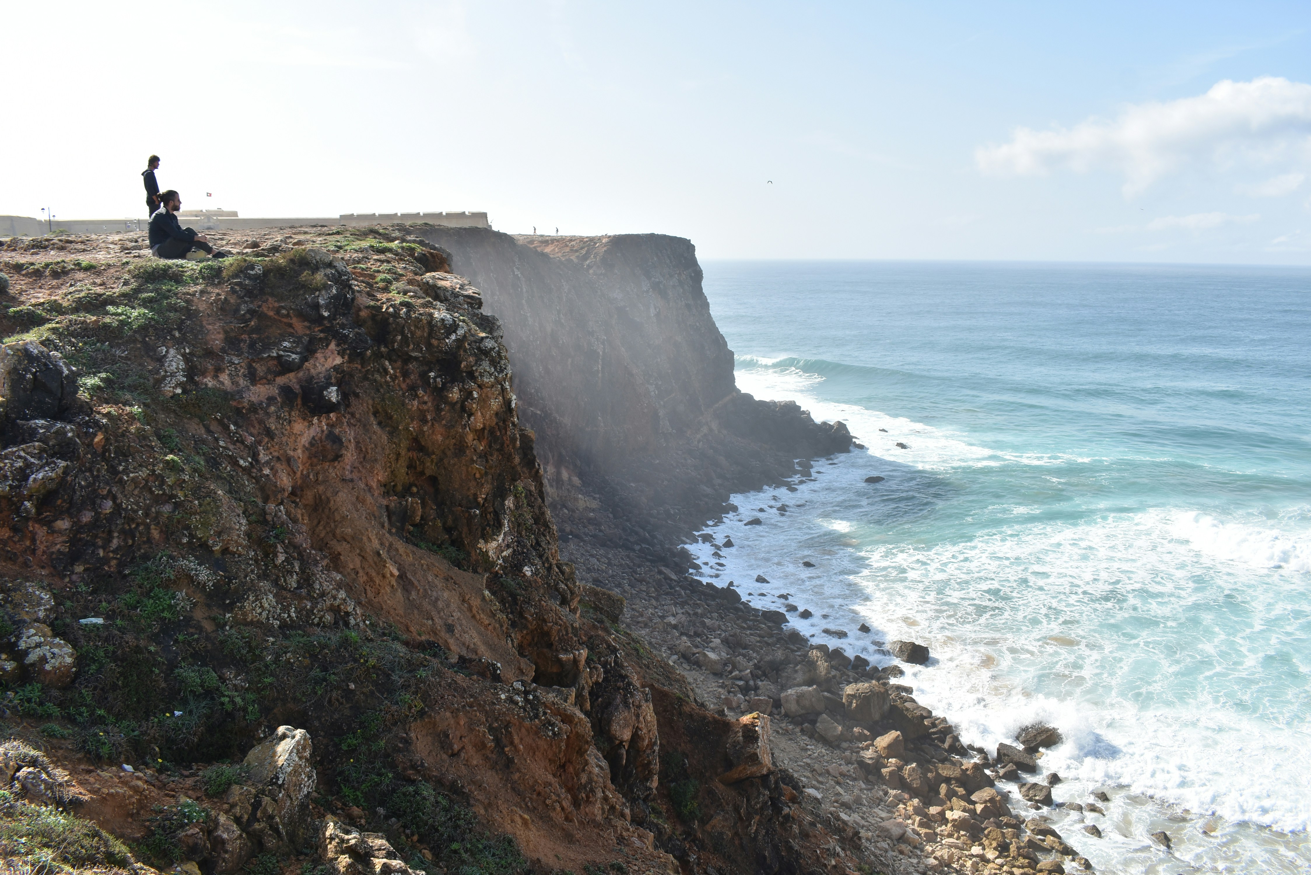brown rocky mountain beside sea during daytime